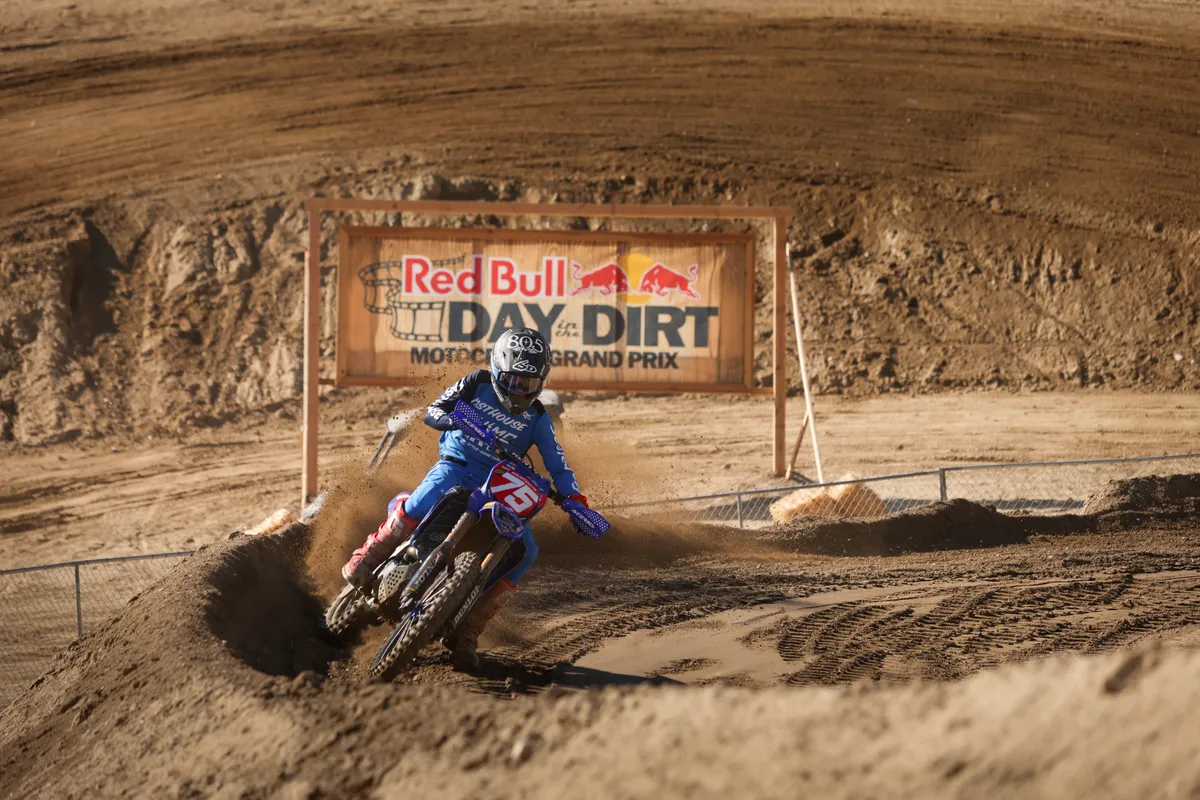 Trevor Stewart carving a dusty berm beneath the Red Bull Day in the Dirt banner