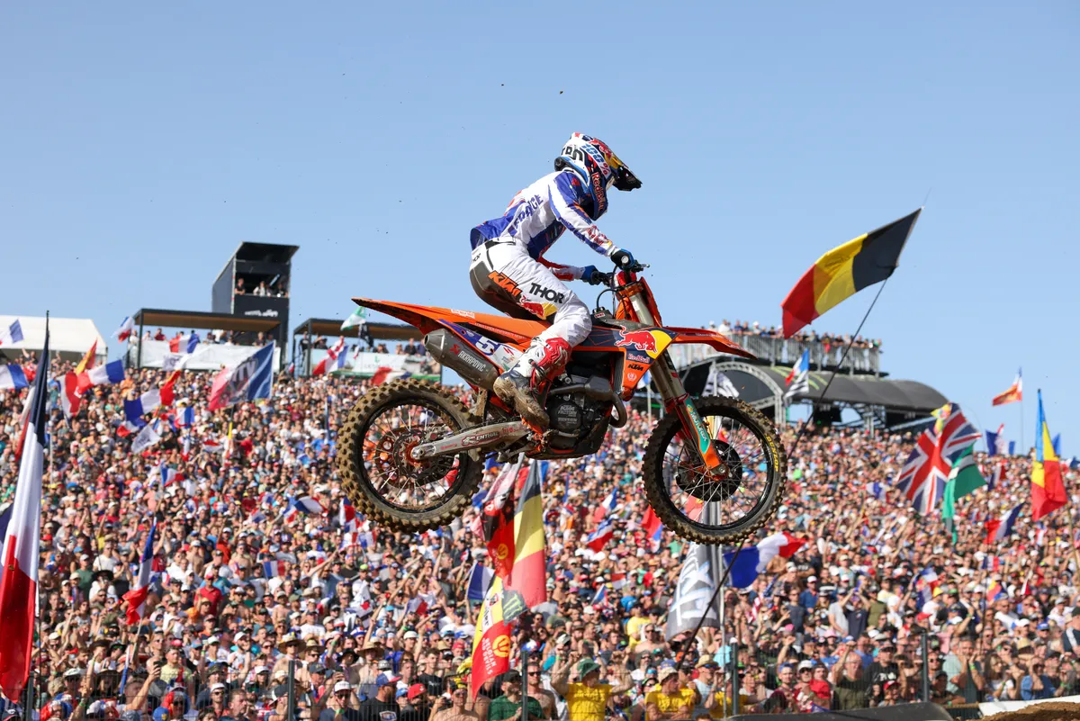 Tom Vialle flying high over a hillside packed with fans and flags at the Motocross of Nations in Ernée