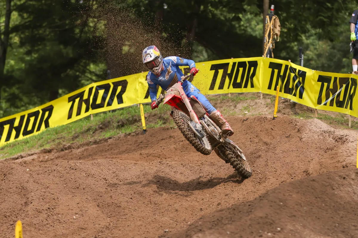 Motocross rider railing a berm past Thor banners at Southwick