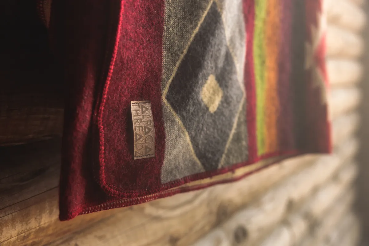 Close-up of a patterned wool blanket and its leather Alpaca Threadz tag