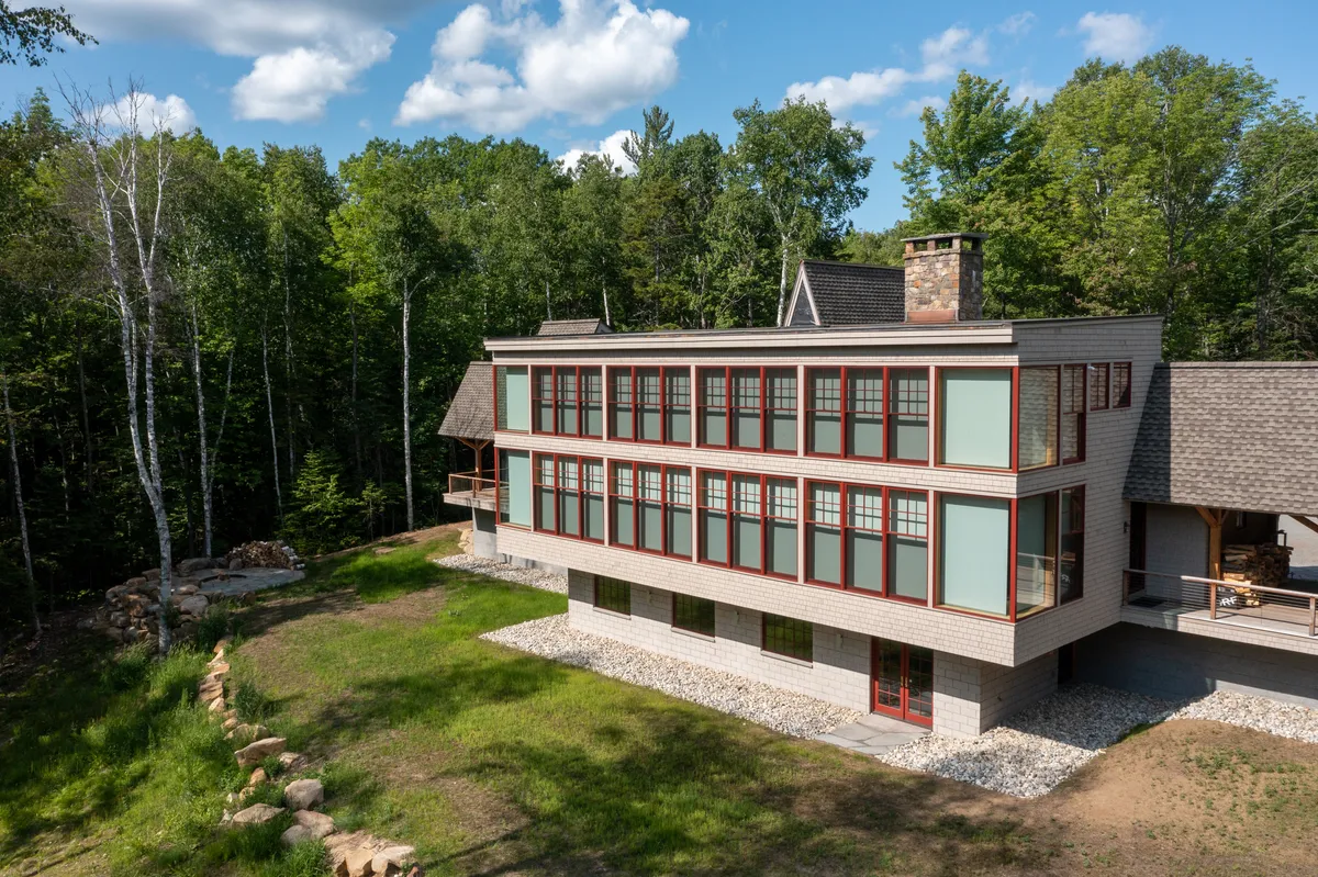 Three-story home with long bands of windows set in a clearing in the forest