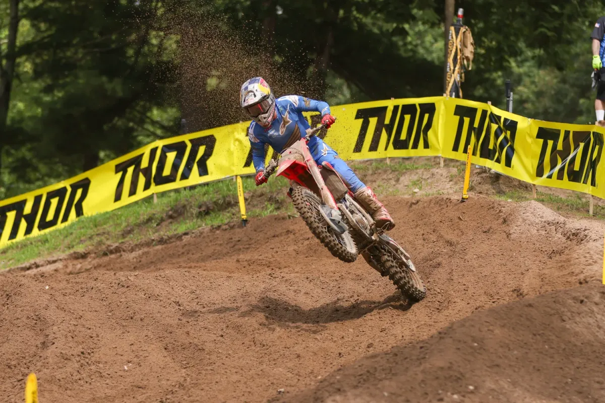 Motocross rider railing a berm past Thor banners at Southwick