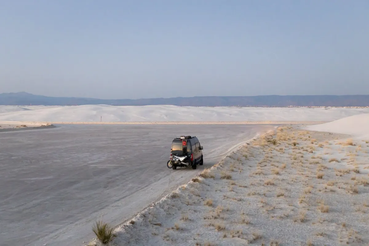 Van driving the hard-packed sand road through the dunes