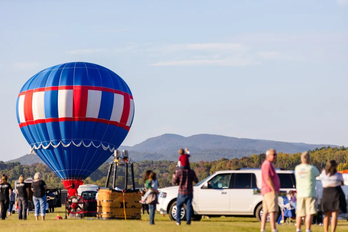 Red, white and blue balloon inflating in front of the Adirondacks