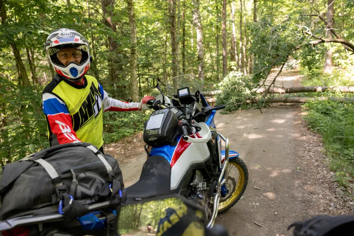 Adventure rider in a helmet beside his motorcycle on a trail