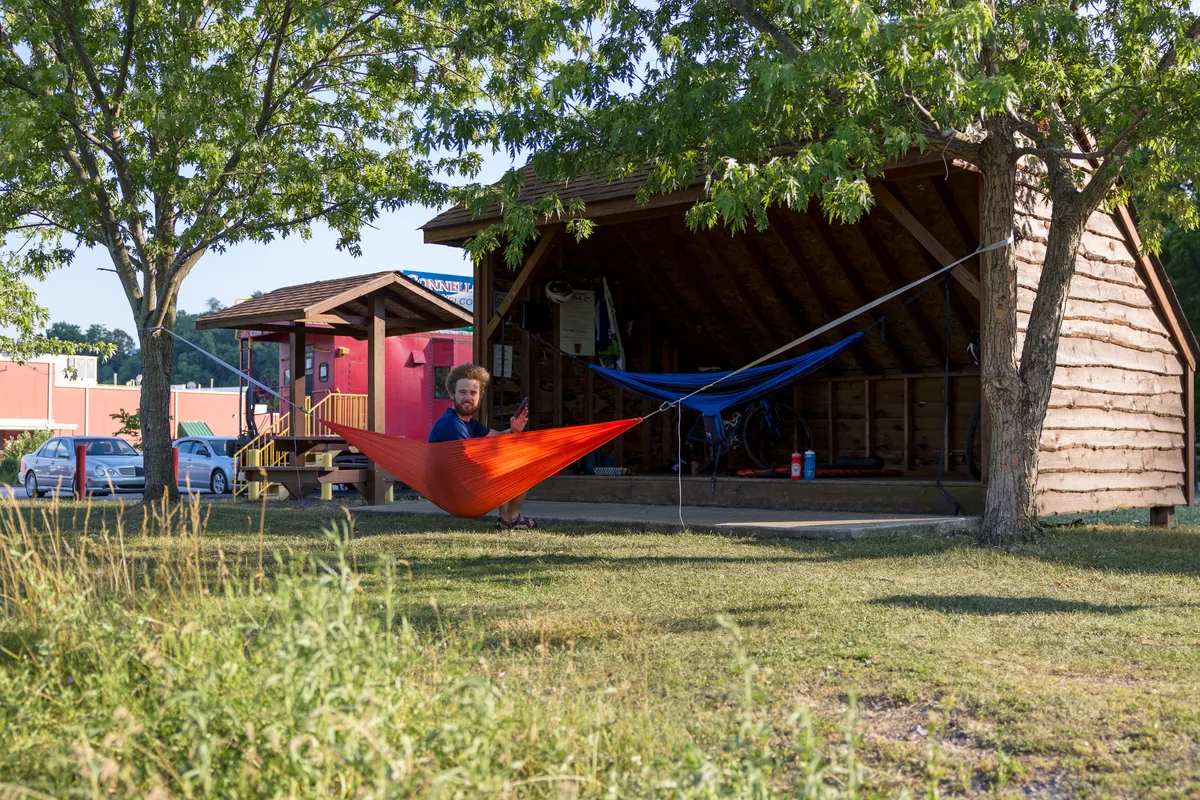 Dan relaxing in an orange hammock strung by an Adirondack shelter