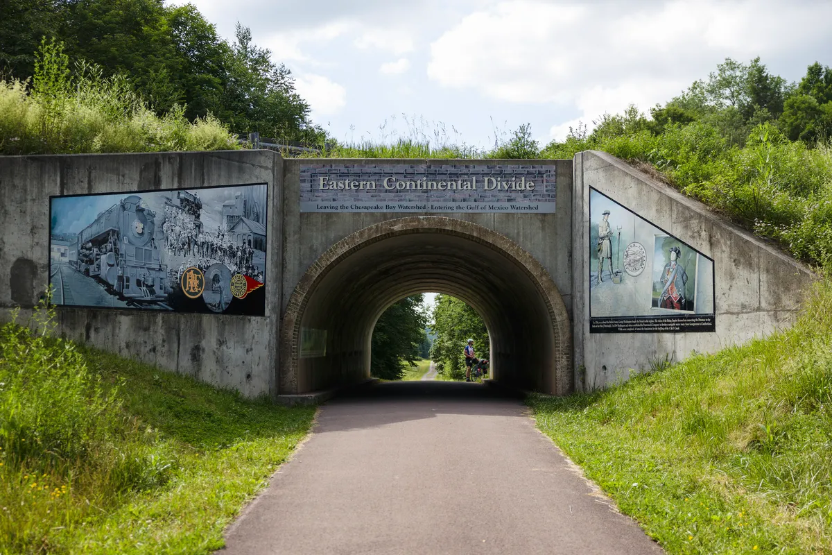 Trail tunnel under the road with murals and the Eastern Continental Divide sign above