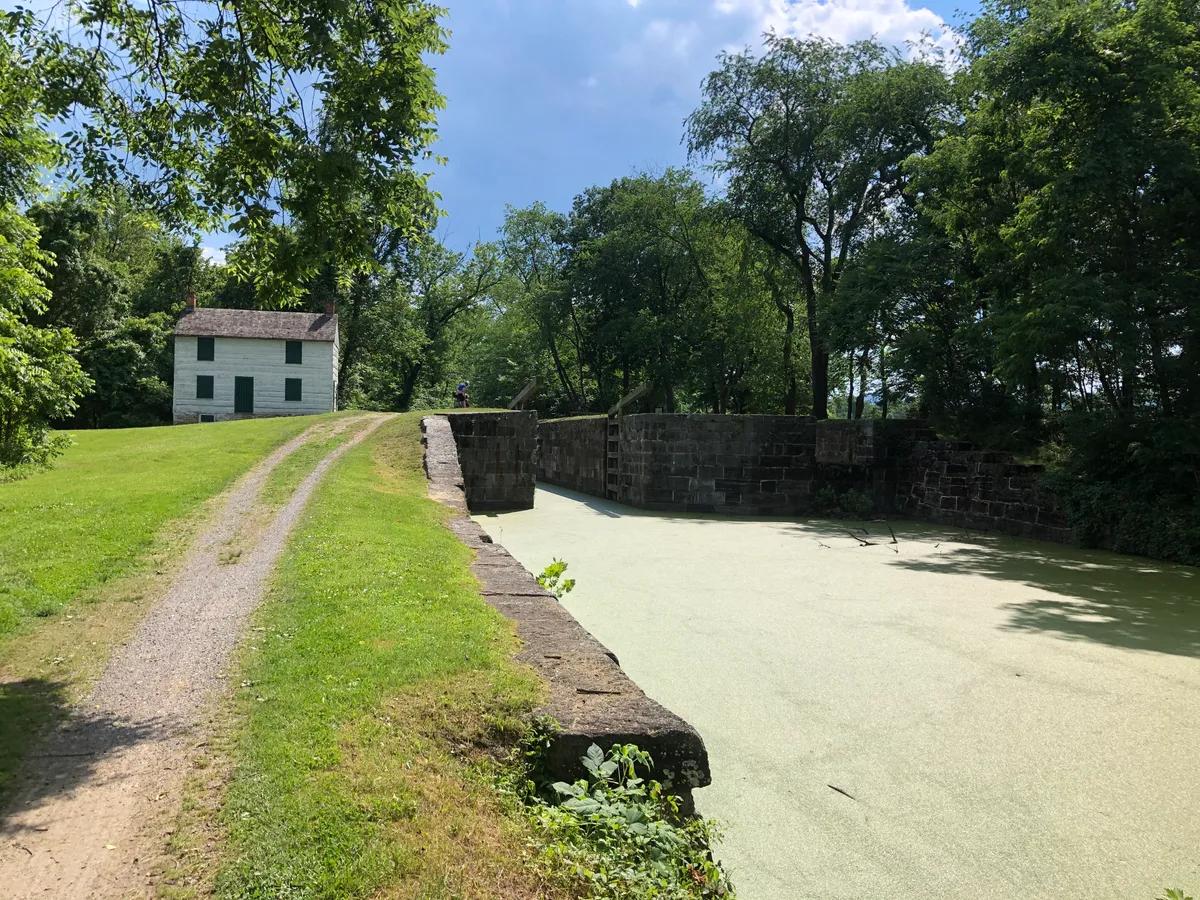 White canal lockkeeper's house beside a dry, grassy lock