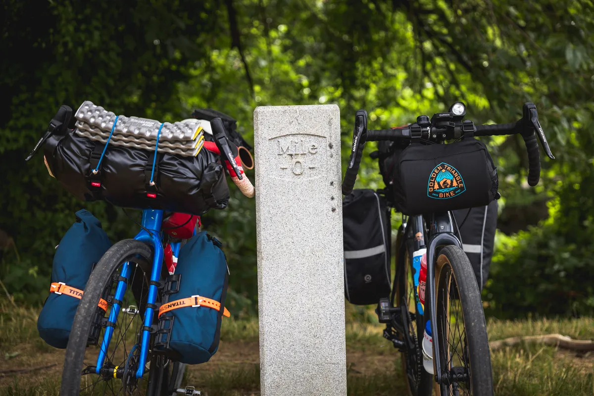 Two loaded bikes on either side of the C&O Canal Mile 0 stone marker