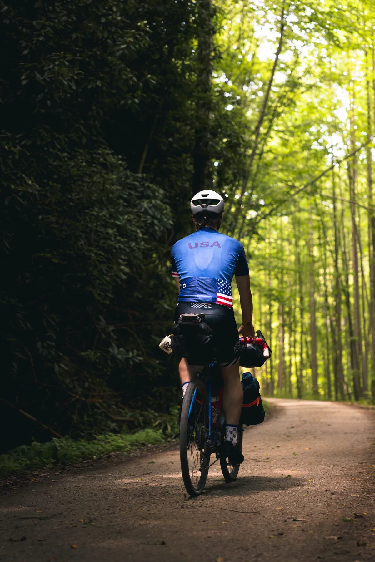 Dan in a USA jersey riding a shaded, leafy section of trail in Ohiopyle State Park
