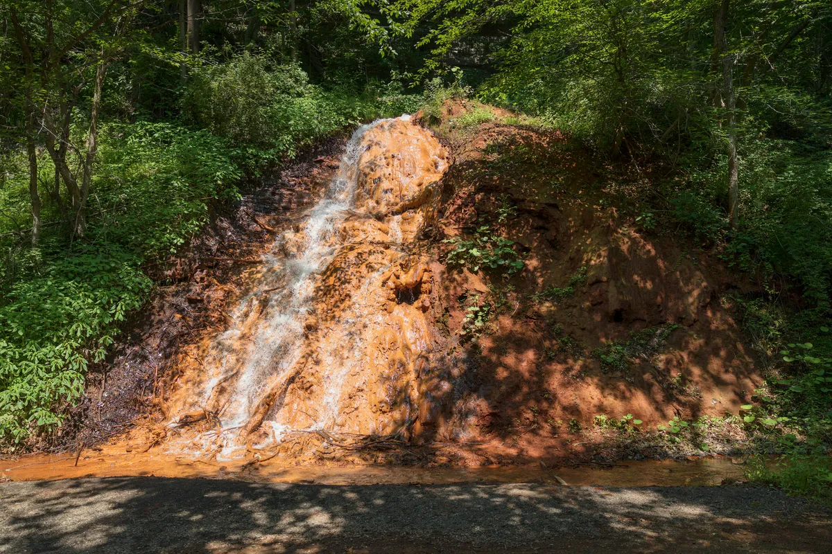 Orange, iron-stained waterfall trickling down a hillside
