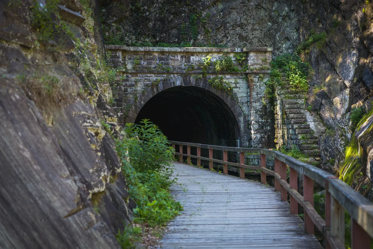 Stone portal of the Paw Paw tunnel with the wooden boardwalk railing leading in