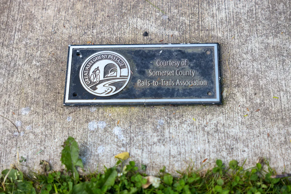 Plaque set in concrete reading Courtesy of Somerset County Rails-to-Trails Association, with the GAP logo