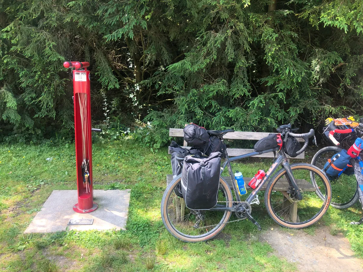 Red bike repair stand beside a bench with the loaded bikes