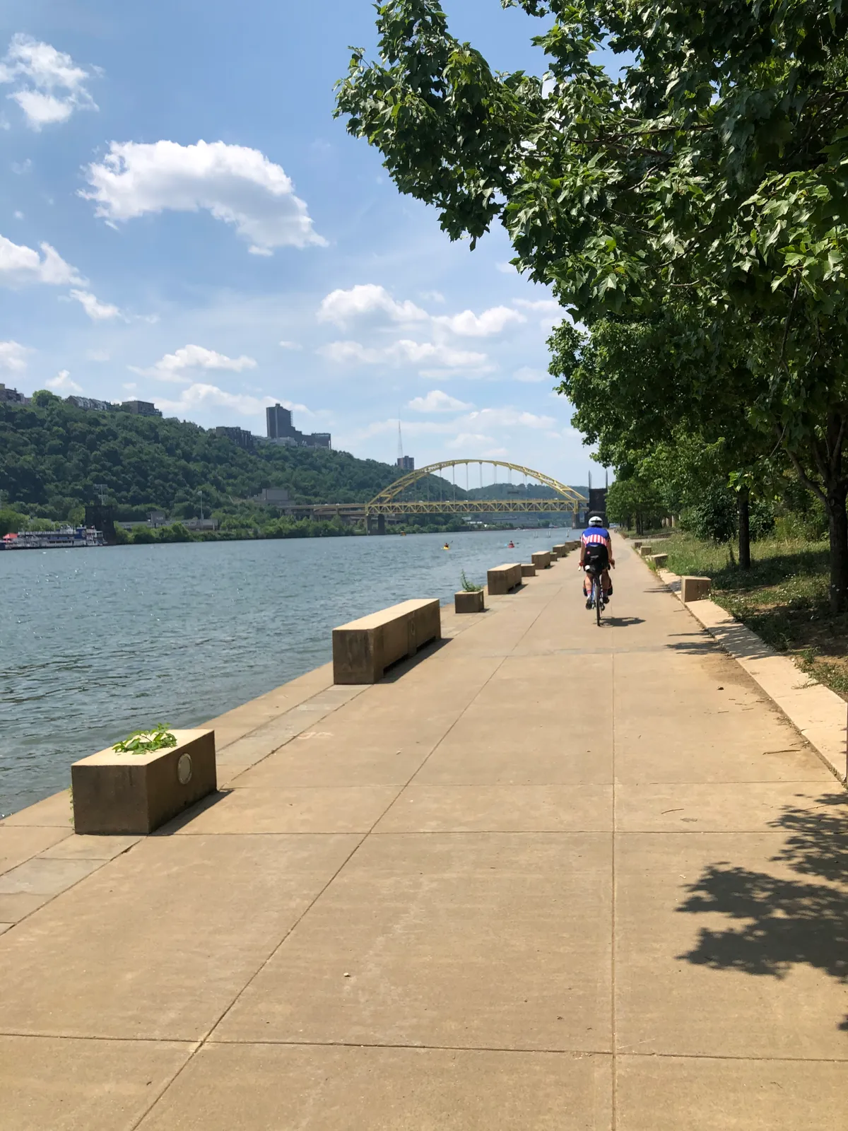 Dan riding the riverside path toward Pittsburgh with a yellow bridge in the distance