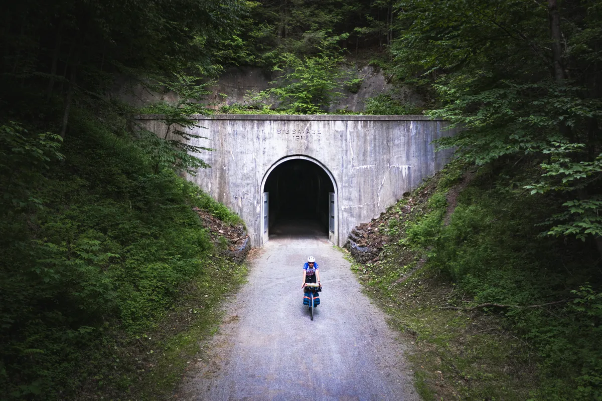 Dan riding out of a concrete tunnel portal in the woods