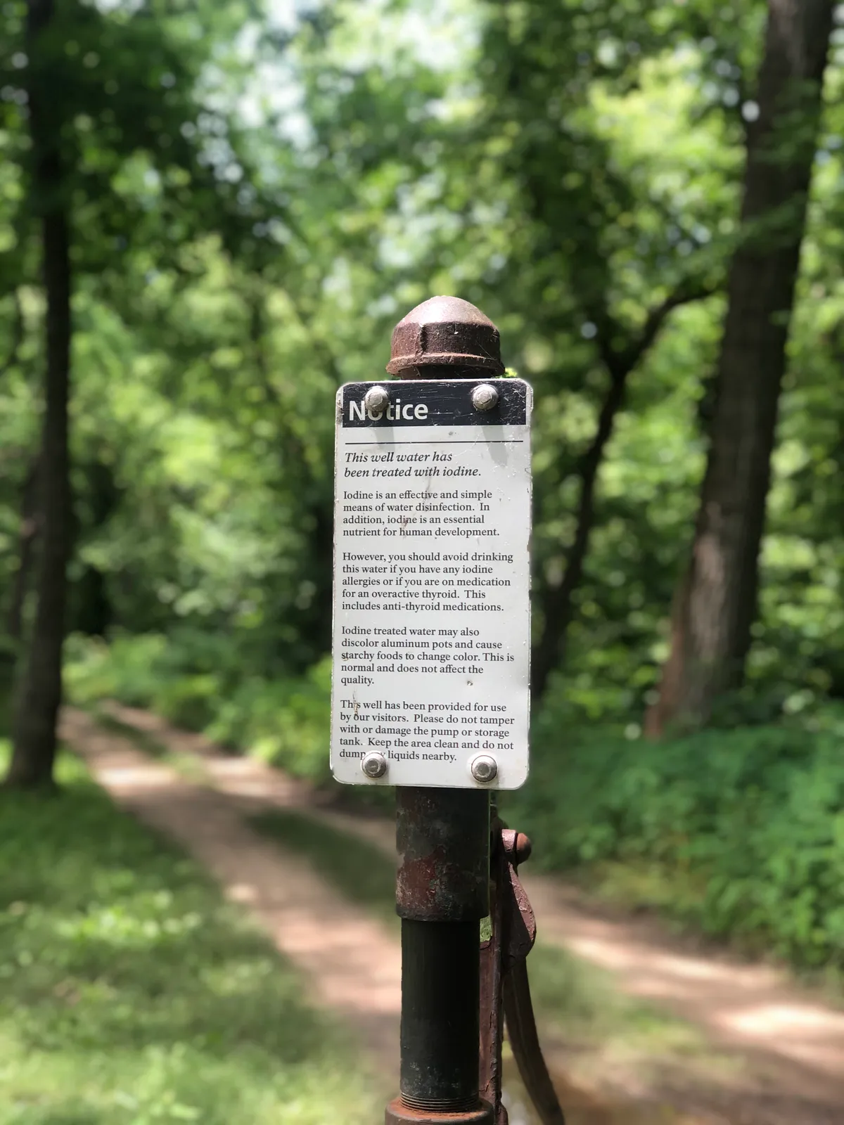 Close-up of the pump's notice that the well water has been treated with iodine, trail blurred behind