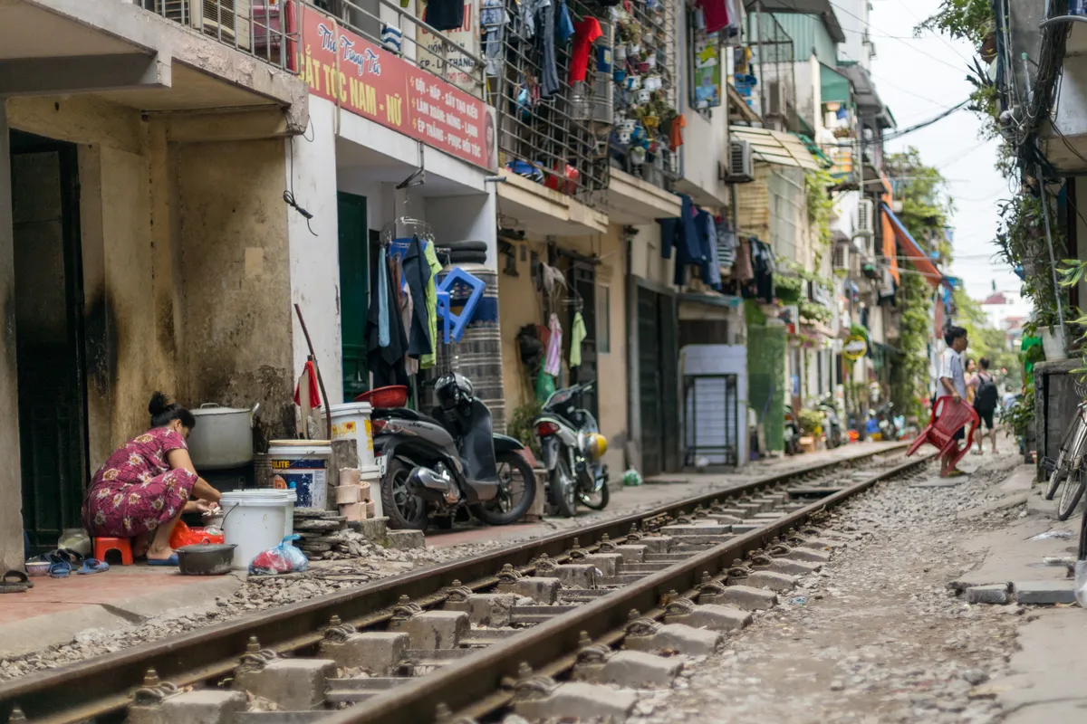 Woman cooking at her doorstep beside the rails