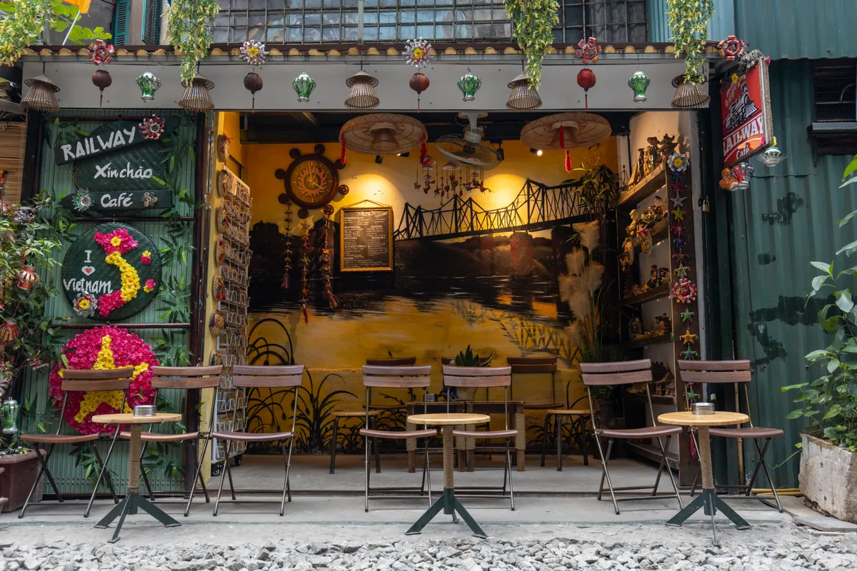 Railway cafe front with an I love Vietnam flower sign and chairs set out on the tracks