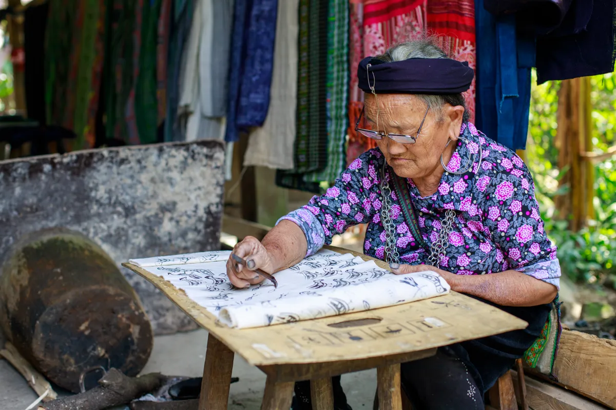 H'Mông woman drawing designs onto white fabric