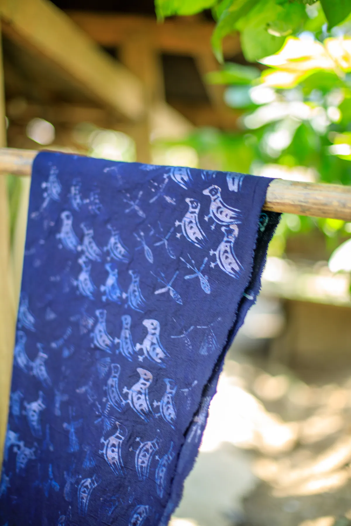 Finished indigo cloth with a white bird pattern hanging from a pole