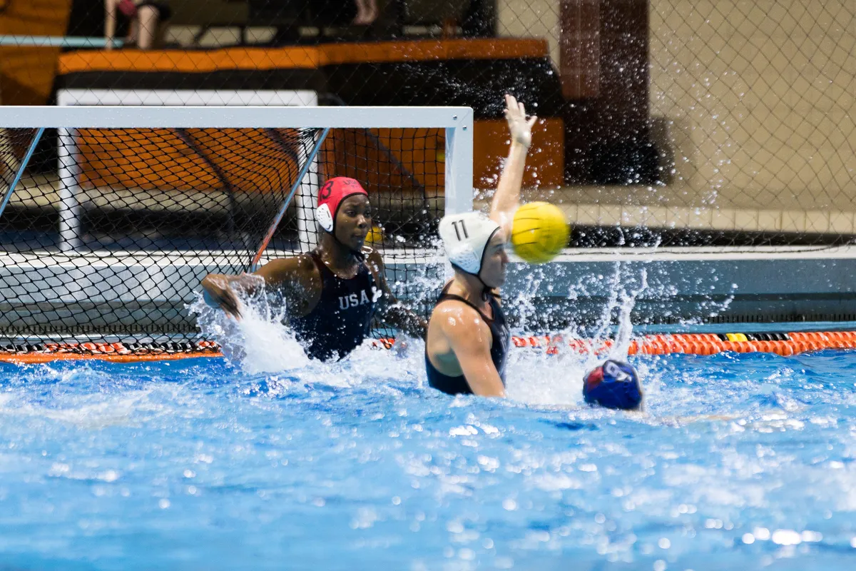 USA goalkeeper beside USA number 11 as she blocks a shot near the goal
