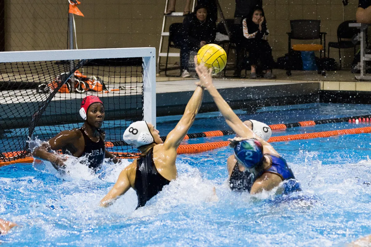 Two USA defenders leaping to block a shot in front of their goalkeeper