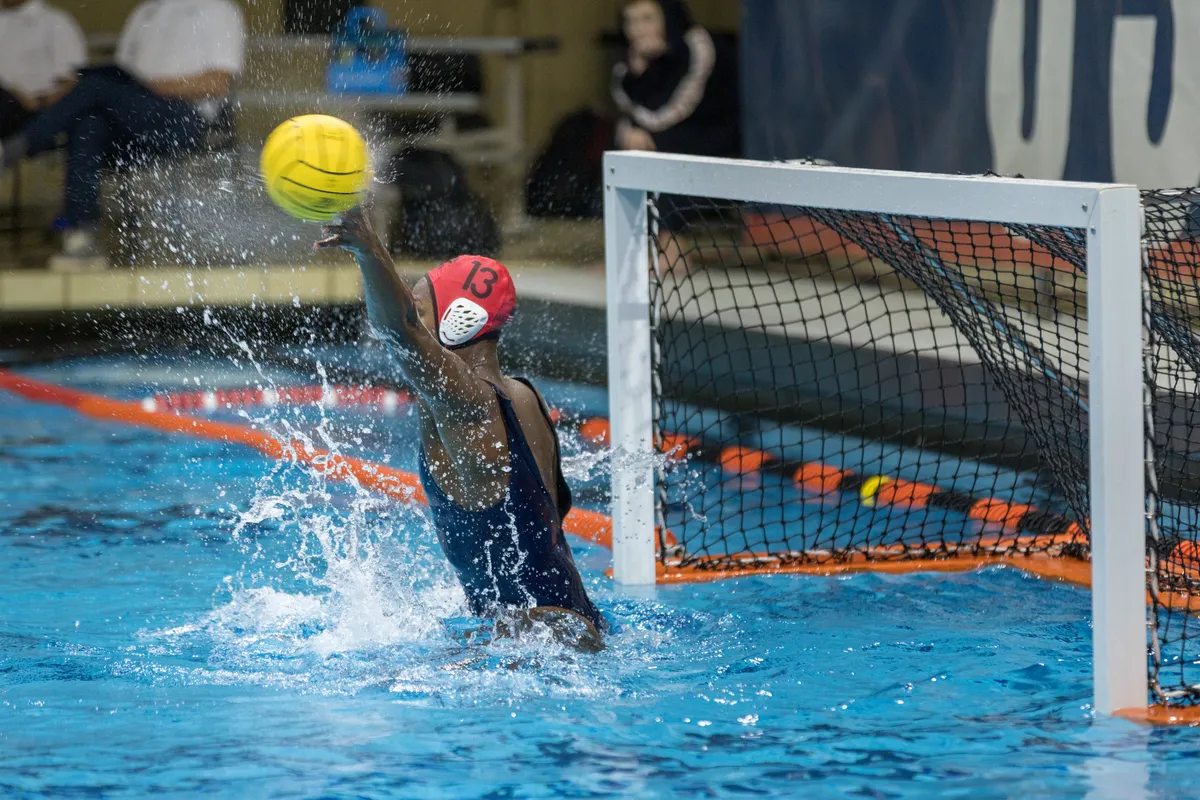 USA goalkeeper number 13 reaching up with one hand to meet the ball