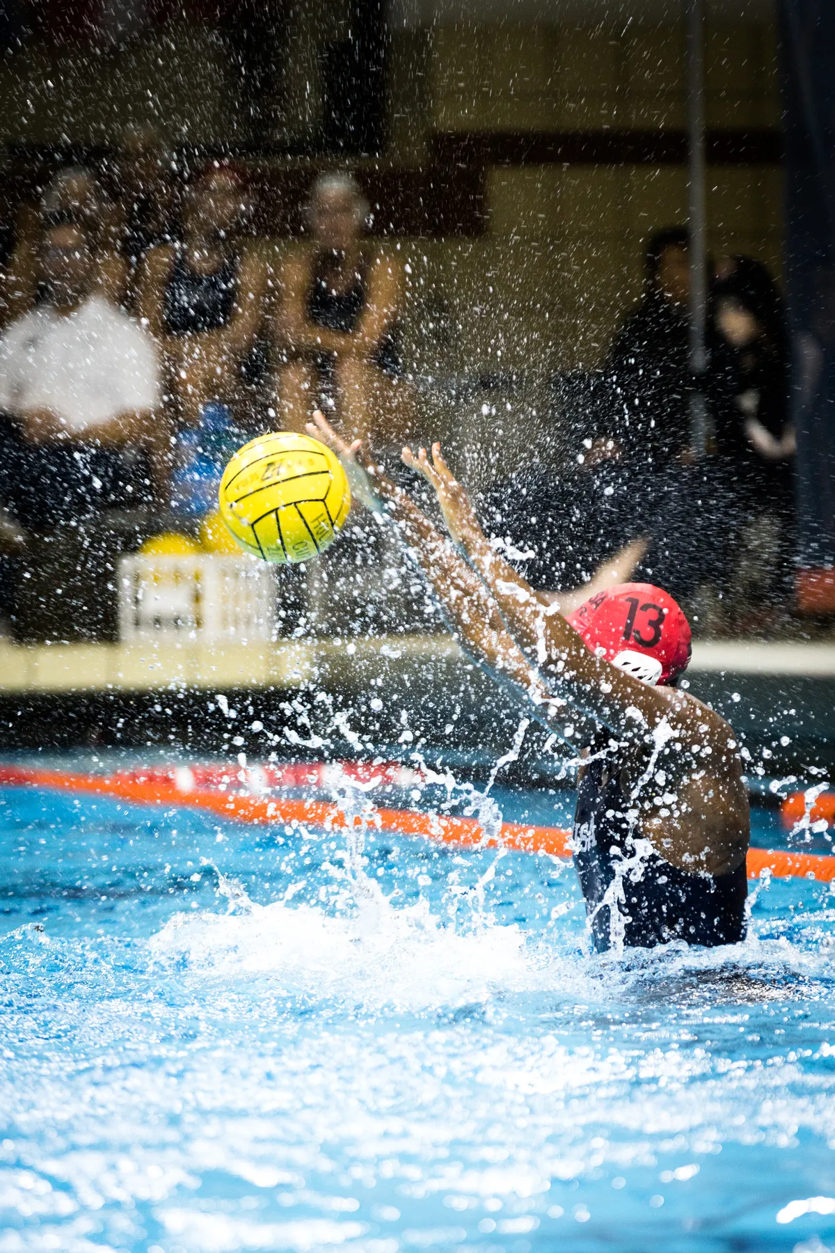 USA goalkeeper leaping through the spray with the ball overhead