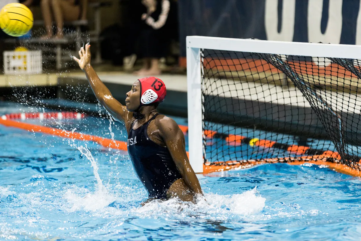 USA goalkeeper in a red cap reaching up as the ball flies past, goal behind her