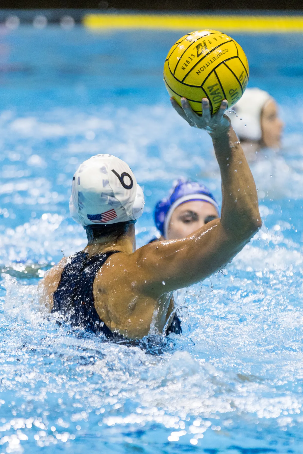 USA number 6 holding the ball up to pass with an Italian defender behind her