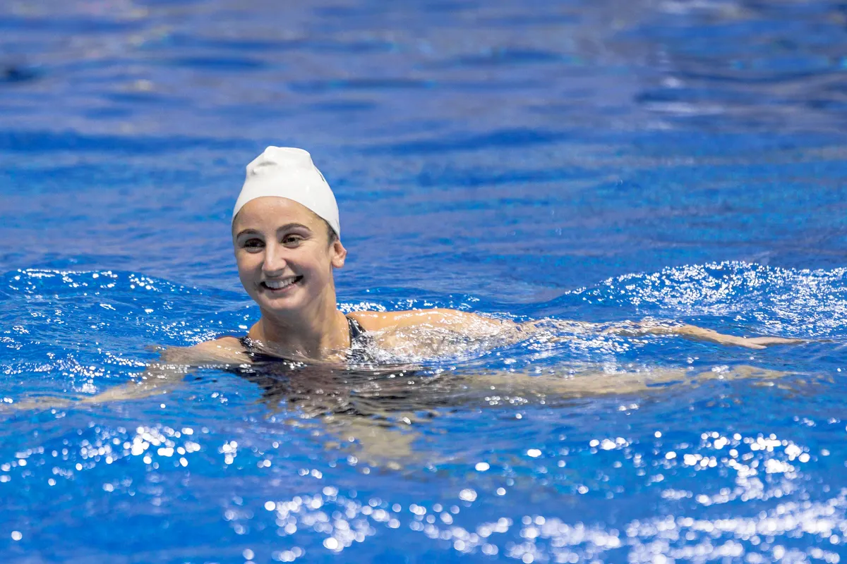USA player in a white cap smiling while treading water during warm-ups