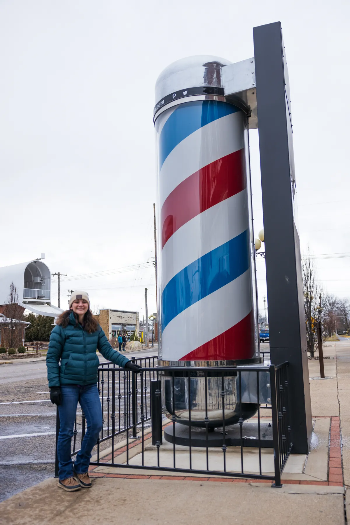 Visitor standing next to a giant red, white and blue barber pole