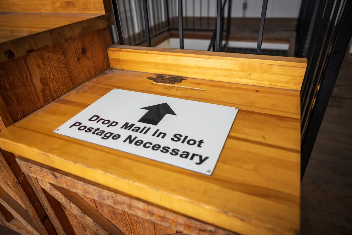 Sign inside the mailbox reading Drop Mail in Slot, Postage Necessary
