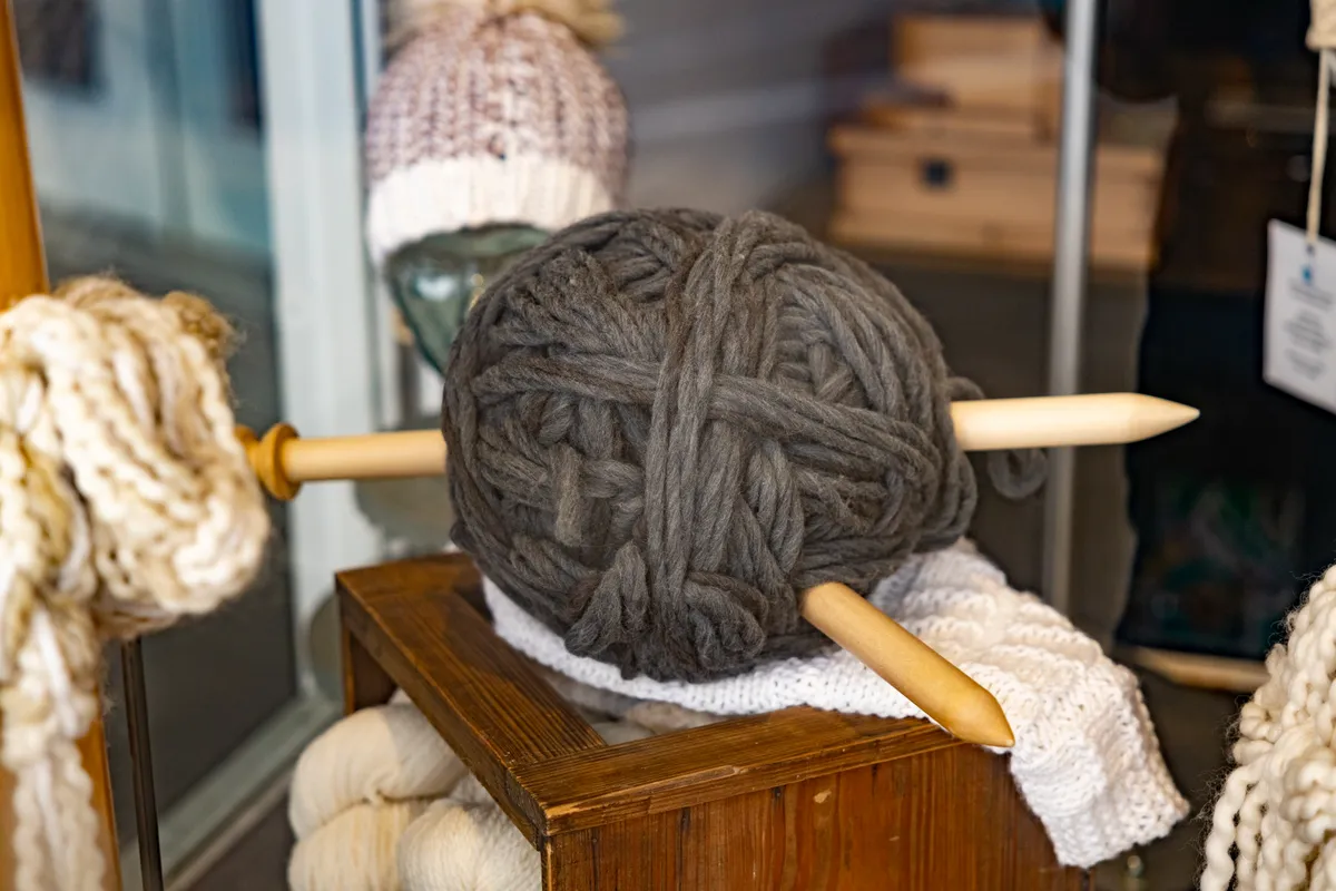 Giant ball of yarn pierced by oversized knitting needles in a shop