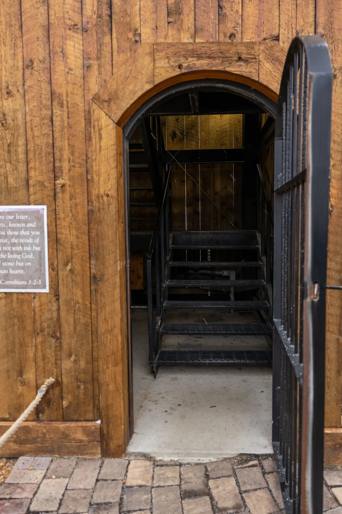 Arched wooden door with stairs leading up inside the mailbox post