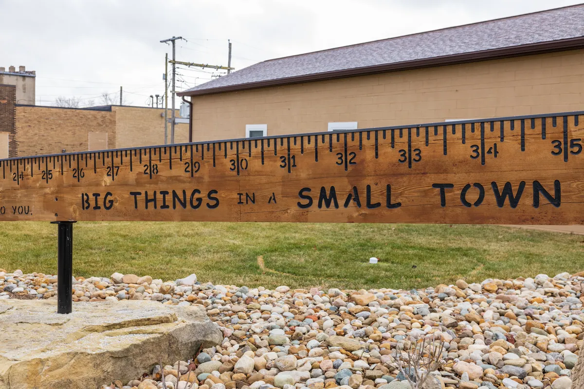 Giant wooden yardstick sign reading Big Things in a Small Town