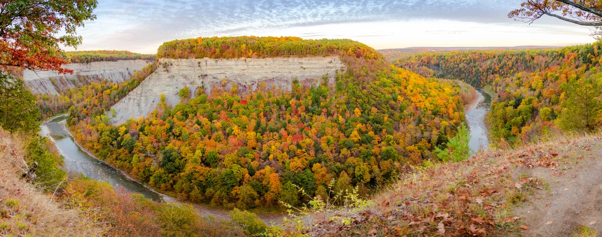 Panorama of a river bending around a cliff-walled gorge covered in autumn foliage