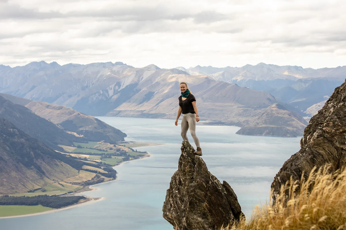 Hiker standing on a rock pinnacle above a mountain lake